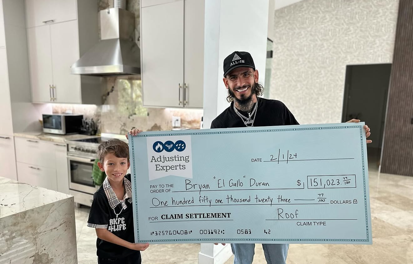 Bryan El Gallo Duran receiving a $151,023.77 roof claim settlement check from Adjusting Experts