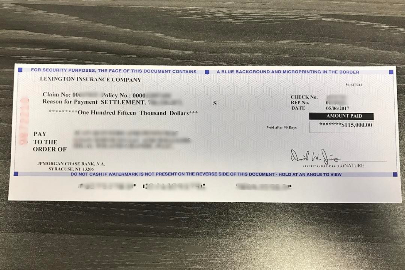 Adjusting Experts client receiving a $115,000.00 insurance settlement check